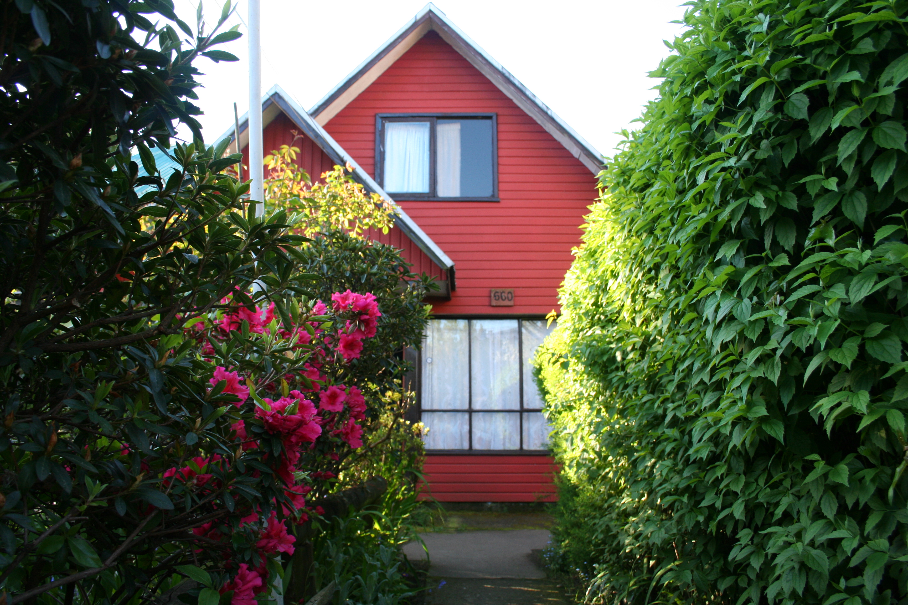 Casa de madera de dos pisos con un gran jardín delantero y estacionamiento.